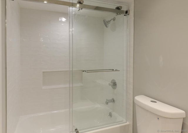 full bath featuring toilet and shower / bath combination with glass door