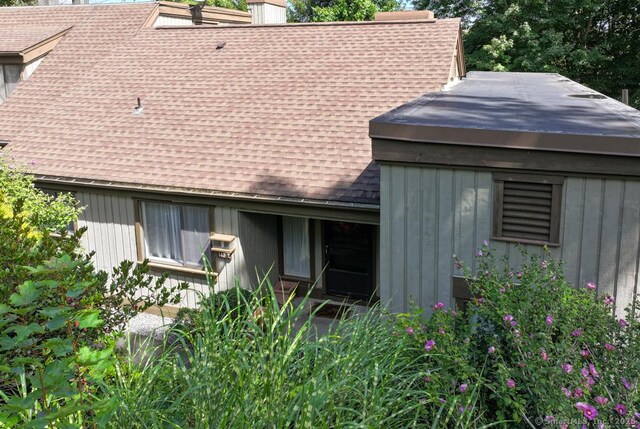 exterior space with a chimney and roof with shingles