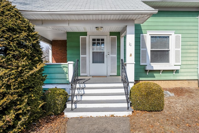 property entrance featuring a shingled roof and covered porch