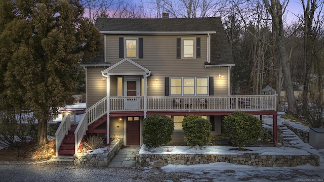 view of front of home with stairs, a shingled roof, and a chimney