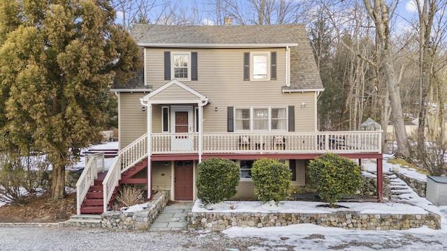 view of front of home featuring a shingled roof, a chimney, stairway, and a wooden deck