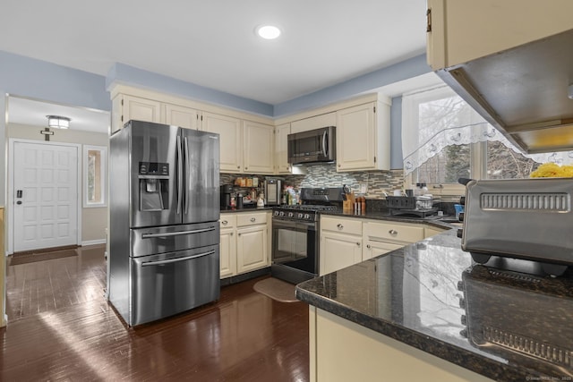 kitchen featuring dark wood-style floors, stainless steel appliances, dark stone counters, and decorative backsplash