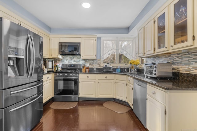 kitchen with a toaster, dark wood-style floors, glass insert cabinets, stainless steel appliances, and backsplash