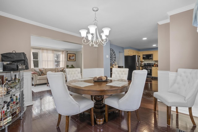 dining space featuring dark wood-style flooring, wainscoting, crown molding, and an inviting chandelier