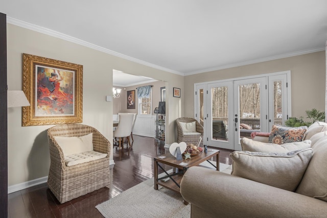 living room with dark wood-style flooring, french doors, crown molding, a notable chandelier, and baseboards