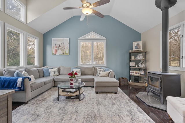 living room with vaulted ceiling, dark wood finished floors, a wood stove, and a healthy amount of sunlight