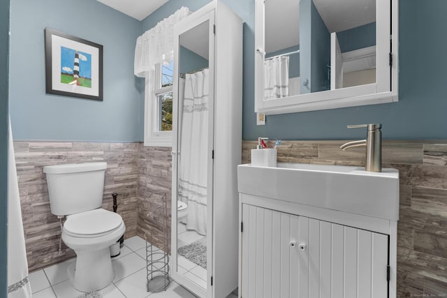 full bath featuring tile patterned flooring, toilet, a wainscoted wall, vanity, and tile walls