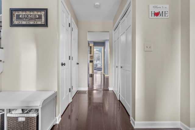 corridor with dark wood-type flooring and baseboards