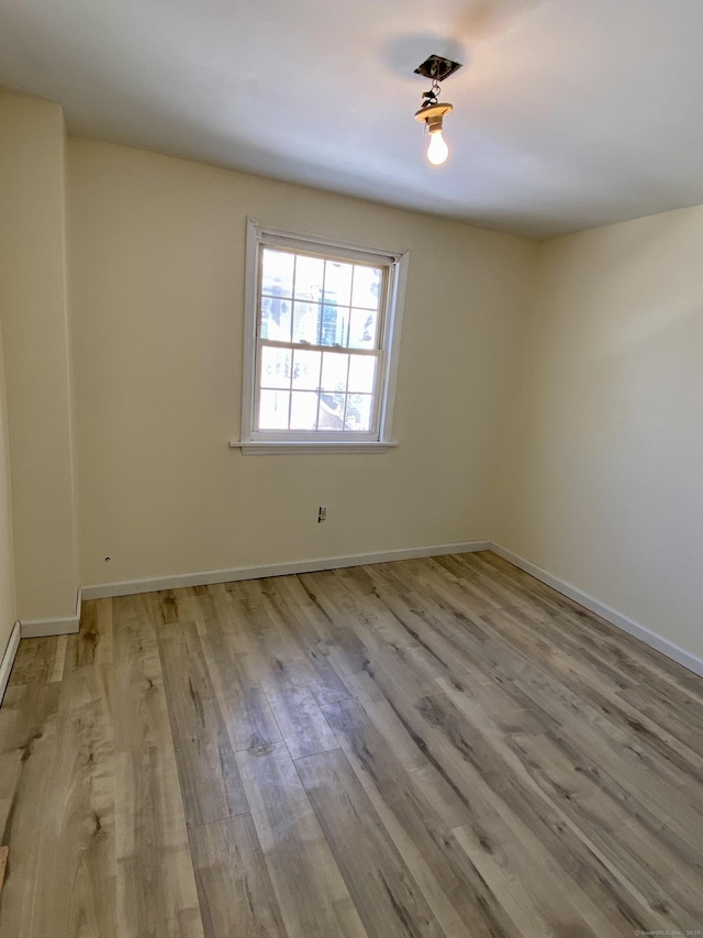 spare room with baseboards and wood finished floors