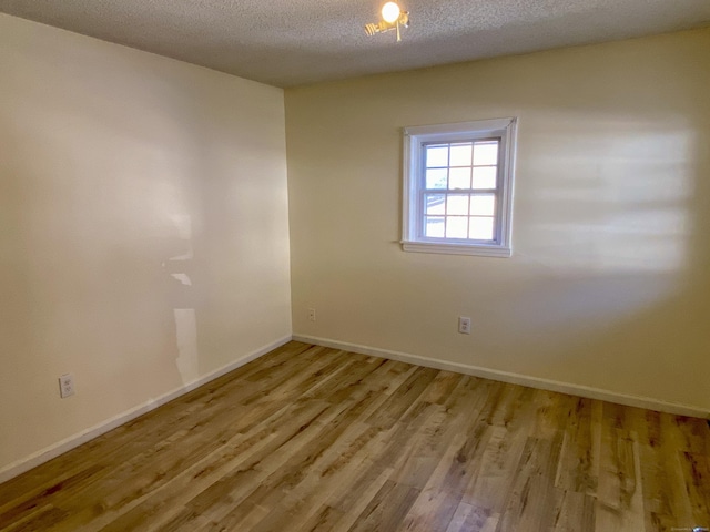 unfurnished room featuring a textured ceiling, baseboards, and wood finished floors