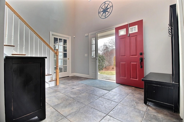 foyer with stone tile floors, stairs, and baseboards