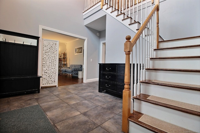 foyer with a high ceiling, stairway, and baseboards