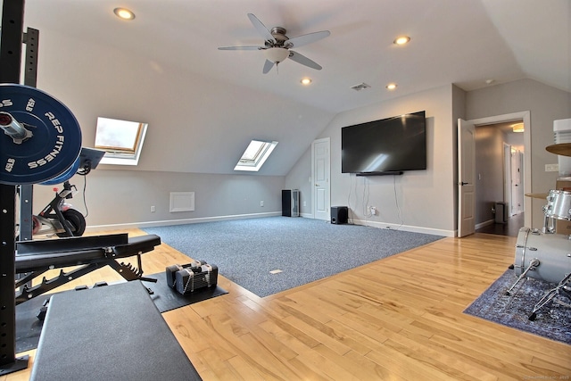 exercise room featuring vaulted ceiling with skylight, baseboards, wood finished floors, and recessed lighting