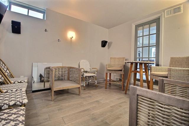 living area with light wood-type flooring, visible vents, and baseboards