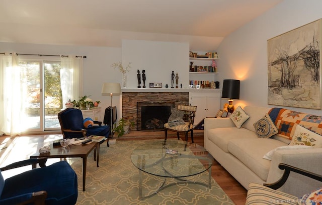 living area featuring a stone fireplace and wood finished floors