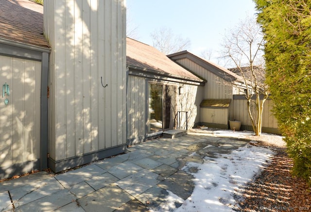 view of home's exterior with a patio and roof with shingles