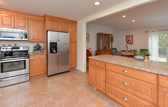 kitchen featuring recessed lighting, light stone countertops, appliances with stainless steel finishes, and brown cabinets
