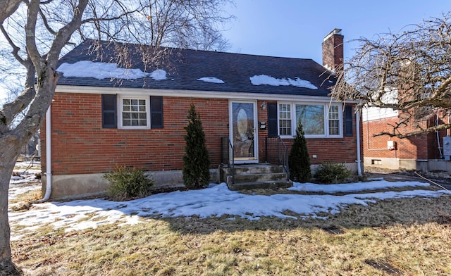 view of front of home with brick siding, a chimney, and roof with shingles