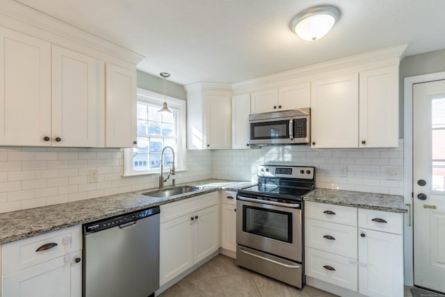 kitchen featuring white cabinets, decorative backsplash, light stone countertops, stainless steel appliances, and a sink