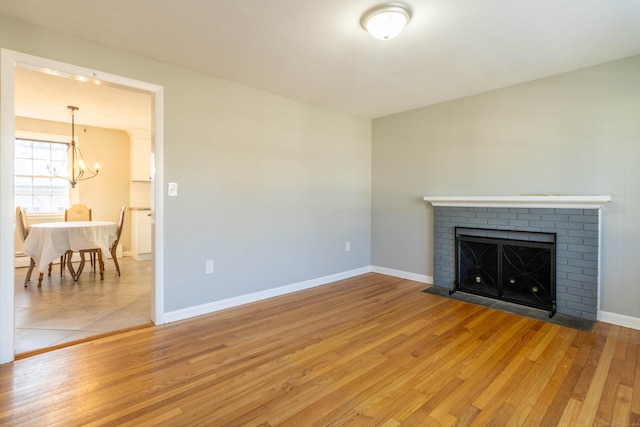 living area featuring a brick fireplace, baseboards, and wood finished floors