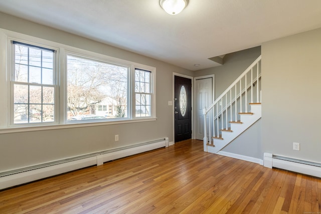 entrance foyer featuring a baseboard heating unit, stairs, light wood-style flooring, and baseboards