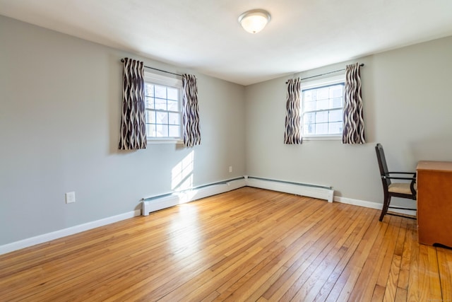 unfurnished office with light wood-type flooring, a baseboard radiator, a wealth of natural light, and baseboards