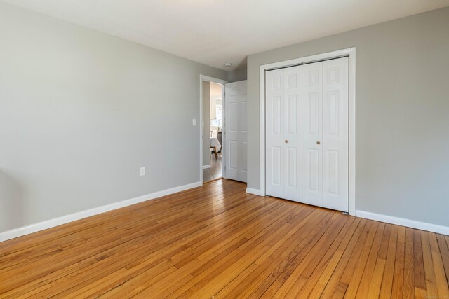 unfurnished bedroom with light wood finished floors, a closet, and baseboards