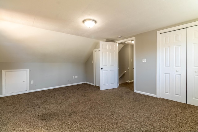 bonus room with vaulted ceiling, dark carpet, and baseboards