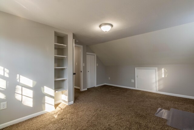 additional living space with vaulted ceiling, carpet, built in features, and baseboards