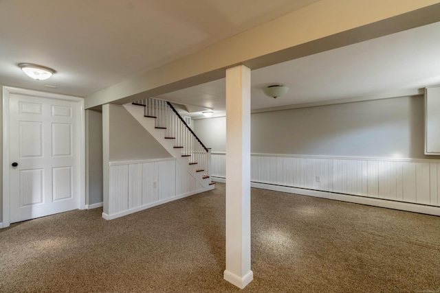 finished basement with carpet, a wainscoted wall, stairway, and a baseboard radiator