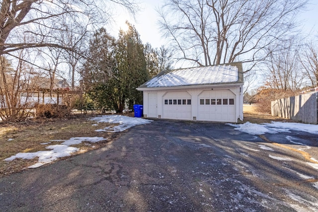 snow covered garage with a detached garage and fence