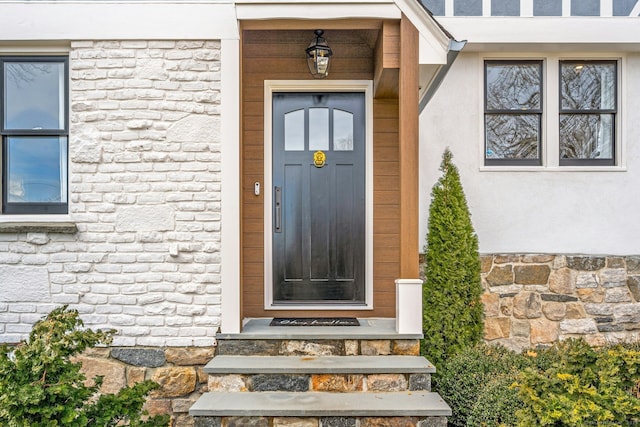 view of exterior entry featuring stone siding and stucco siding