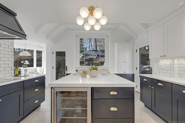 kitchen featuring beverage cooler, custom range hood, backsplash, white cabinetry, and light countertops