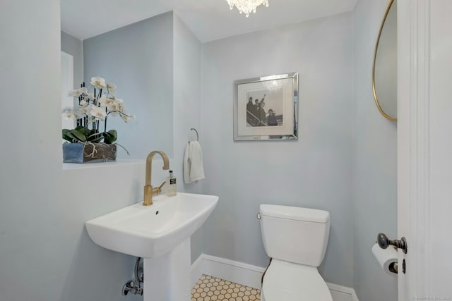 half bath with a sink, baseboards, toilet, and tile patterned flooring