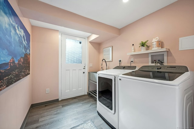 clothes washing area with light wood finished floors, laundry area, independent washer and dryer, and baseboards