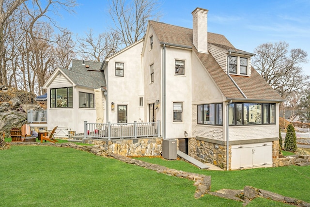 back of property featuring a shingled roof, stucco siding, a lawn, cooling unit, and a chimney