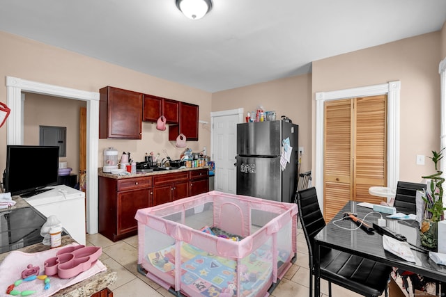 kitchen featuring light tile patterned floors, freestanding refrigerator, light countertops, dark brown cabinets, and washing machine and dryer