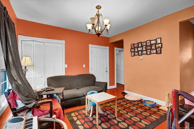 living area with baseboards, an inviting chandelier, and wood finished floors