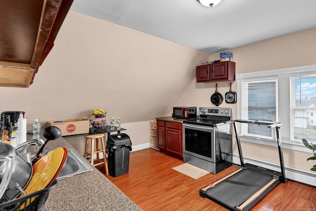 kitchen with light wood finished floors, a baseboard heating unit, stainless steel range with electric stovetop, black microwave, and a sink