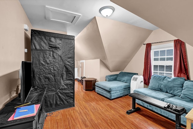 living room with light wood-style floors, attic access, and vaulted ceiling