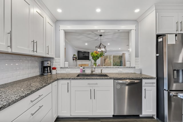 kitchen with stainless steel appliances, white cabinetry, a sink, and backsplash