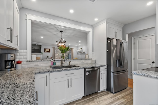 kitchen with light stone counters, a sink, white cabinets, appliances with stainless steel finishes, and light wood-type flooring