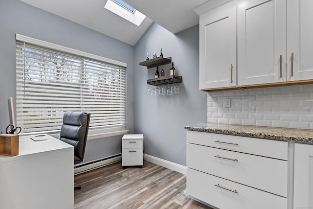 unfurnished office with vaulted ceiling with skylight, a baseboard radiator, baseboards, and light wood-style flooring