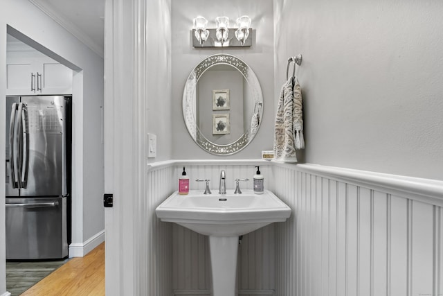 bathroom with a sink, ornamental molding, wood finished floors, and wainscoting