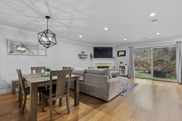 dining area featuring light wood-style floors, recessed lighting, a fireplace, and crown molding