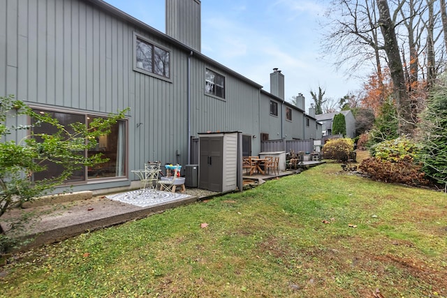 rear view of property featuring a patio area, central AC, a lawn, and a chimney