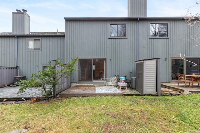 rear view of house with a patio, a lawn, and a chimney