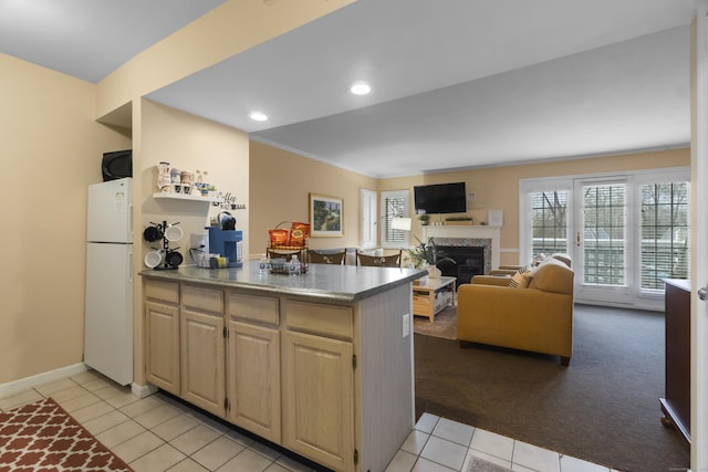 kitchen featuring light tile patterned floors, light brown cabinets, a fireplace, open floor plan, and freestanding refrigerator