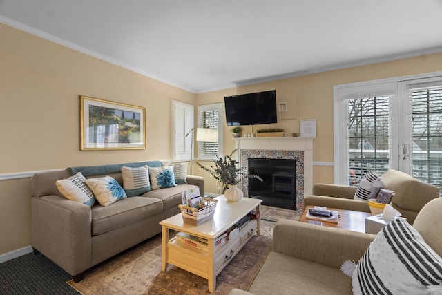 living room with baseboards, crown molding, and a glass covered fireplace