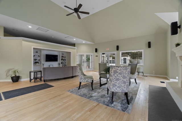 dining room featuring french doors, a fireplace with raised hearth, wood finished floors, high vaulted ceiling, and baseboards